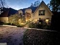 Well-lit home exterior at dusk with a brick driveway and lush greenery at 275 Old Mill Ct, Fayetteville, GA 30214