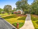 Beautiful brick home with a long driveway, landscaped yard, and mature trees at 830 Streamside Dr, Mcdonough, GA 30252