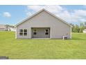 Rear exterior view of a gray home with a covered patio and a spacious green lawn at 1009 Claas Way, Locust Grove, GA 30248