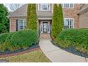 Close up of a home's entry way, with a pathway leading to the front door flanked by manicured greenery at 135 Edgewater Trl, Fayetteville, GA 30215