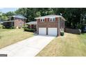 View of home, lawn and long driveway leading to a two-car garage on a sunny day at 3216 Pheasant Dr, Decatur, GA 30034