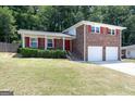 Inviting brick home with red accents, a covered porch, two-car garage, and a spacious front yard at 3216 Pheasant Dr, Decatur, GA 30034