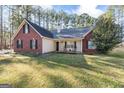Charming red brick home featuring black shutters, a well-manicured lawn, and a cozy front porch with rocking chairs at 1012 Matthews Way, Mcdonough, GA 30252