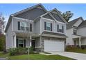Charming two-story home with a gray exterior, stone accents, attached two car garage and a well manicured lawn at 9068 Jim Purcell Dr, Covington, GA 30014
