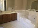 Bathroom featuring double sinks, a soaking tub and tile floors at 1574 Elizabeth Ln, Hampton, GA 30228