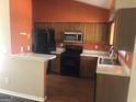 Traditional kitchen with warm wood cabinets, black appliances, and a peninsula counter at 1574 Elizabeth Ln, Hampton, GA 30228