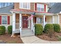 Inviting front porch with American flag, white railings, red door and trim, and well-manicured landscaping at 190 Bridgemill Dr, Hampton, GA 30228