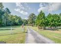 Home's long driveway framed by a charming white fence and lush greenery at 677 Gum Creek Rd, Oxford, GA 30054