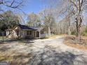 Home exterior with gravel driveway, surrounded by mature trees and a fenced yard at 927 Dean Patrick Rd, Locust Grove, GA 30248