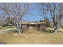 Front exterior with mature trees framing a charming brick home with rocking chairs on the porch at 143 Teamon Rd, Hampton, GA 30228