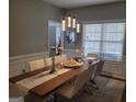 Dining room with a large table set for eight, with a modern chandelier and decorative mirror at 4006 Asheville Ct, Buford, GA 30519