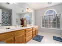 Bright bathroom with double sinks, wooden cabinets, and an arched window overlooking the yard at 149 Crown Oaks Dr, Stockbridge, GA 30281
