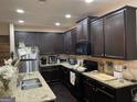An open-concept kitchen features granite countertops, dark wood cabinets and stainless appliances at 6001 Nile Ct, Atlanta, GA 30349
