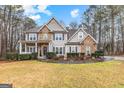 Inviting two-story home with stone and siding exterior, a covered porch, and landscaped yard with mature trees at 65 Ashland Grove Ct, Sharpsburg, GA 30277