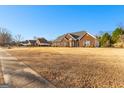 A well-maintained brick home sits on a large lot, showcasing a classic suburban landscape with bright blue skies at 263 Caitlyn Dr, Hampton, GA 30228
