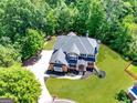 Aerial view of a beautifully landscaped property featuring a large manicured lawn and mature trees surrounding the home at 6690 Bridge Brook Ovlk, Cumming, GA 30028