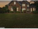 Inviting home with manicured front lawn and garden, with warm interior lights seen from the outside at 1500 Royce Dr, Locust Grove, GA 30248