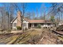 Inviting ranch-style home featuring a brick chimney, complemented by bare trees in a natural setting at 135 Flat Creek Ct, Fayetteville, GA 30214