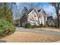 Two car garage and traditional brick home featuring landscaped yard and a circular driveway at 365 Falling Creek Bnd, Johns Creek, GA 30097