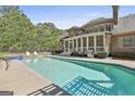 Relaxing pool area with a hot tub, lush landscaping, and an outdoor kitchen, perfect for entertaining guests at 310 Westbourne Dr, Tyrone, GA 30290