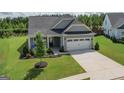 Well-maintained gray home featuring a two-car garage, grassy yard, and inviting front entrance at 104 Conway St, Peachtree City, GA 30269
