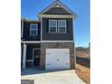 Two-story townhome featuring dark siding, brick base, and a one-car garage in a community setting at 223 Ivey Ter # 34, Temple, GA 30179