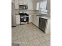Kitchen with stainless appliances, white cabinets, tile flooring, and a double sink at 11187 Shannon Cir, Hampton, GA 30228