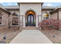 Close up of an elegant front door framed by arched windows and landscaped with small trees at 1198 Elliot Rd, Mcdonough, GA 30252