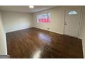 An open living room showcasing beautiful wood floors, a bright window, and a white front door at 975 King James Dr, Morrow, GA 30260