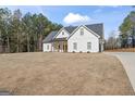 Charming two-story farmhouse with white siding, black roof, rocking chairs, and a well-manicured lawn at 1017 Riverstone Dr, Social Circle, GA 30025