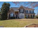 Charming two-story brick home with a well-manicured lawn and mature trees on a sunny day at 5120 Redcoat Ln, Mcdonough, GA 30252