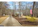 Home surrounded by trees, featuring a long driveway and an American flag at 1191 Rawlings Dr, Rutledge, GA 30663