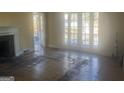 Sunlit living room with fireplace, damaged hardwood floors and French doors leading to an outside balcony at 294 Hascall Nw Rd, Atlanta, GA 30309