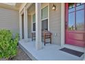 Welcoming front porch boasting a red door, white columns, a cozy bench, and lovely details at 135 Red Maple Dr, Peachtree City, GA 30269