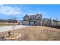 Two-story home featuring a two-car garage, neutral paint, brick accents, and a large driveway at 157 Donovan Ave, Locust Grove, GA 30248