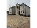 Front of an elegant two-story brick house with stately columns and large windows overlooking the front yard at 829 Artistry Way, Fairburn, GA 30213