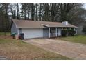 Single story home with a front porch, two car garage, and mature trees in the front yard at 4142 Campbell Rd, Snellville, GA 30039