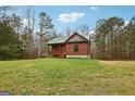 Quaint log cabin with a green metal roof nestled in a peaceful wooded setting with a well-manicured lawn at 1266 Martin Mill Rd, Moreland, GA 30259