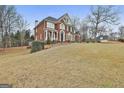 Spacious brick home featuring an impeccable lawn with mature trees and elegant architectural design at 1133 Astoria Ln, Peachtree City, GA 30269