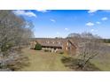 A high angle view of brick home featuring a covered porch, mature trees, and sprawling front yard at 2940 E Lake Rd, Mcdonough, GA 30252