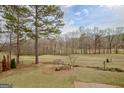 Scenic backyard view featuring a lush lawn, mature trees, and a serene golf course at 2510 Shoreline Pkwy, Villa Rica, GA 30180