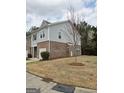 View of the townhome from the side, showing the lawn and a young tree at 1463 River Stone Trce, Conyers, GA 30012