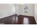 Bright dining room with dark hardwood floors, large windows, and classic white wainscoting at 903 Hollytree Pl, Acworth, GA 30102