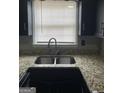 Close-up of a kitchen sink with a window view, granite countertops, and black cabinets at 4477 Golf Vista Cir, Decatur, GA 30035