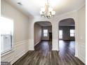 Dining room featuring modern chandelier, wood-look flooring, and an archway view into the living space at 7569 Bowhead Ct, Fairburn, GA 30213