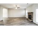 Open living room with a stone fireplace, ceiling fan, and wood-look flooring with a view of the entry archway at 7569 Bowhead Ct, Fairburn, GA 30213