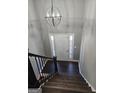 Grand entryway featuring dark wood stairs, modern chandelier, and white door with sidelights at 946 Creek Run Pl, Temple, GA 30179