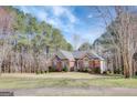 Beautiful single-story home with a brick facade, green lawn and mature trees at 140 Rockglen Ct, Fayetteville, GA 30215
