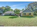 Attractive home with a well-manicured front lawn, stone accents, and mature trees on a sunny day at 880 Brooks Woolsey Rd, Brooks, GA 30205