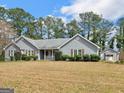 A single-story home with tidy landscaping and a separate garage, all set against a backdrop of tall trees at 230 Acorn Ct, Mcdonough, GA 30253